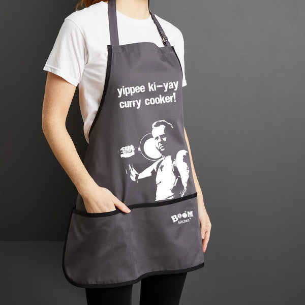 Yippee ki-yay Curry Cooker! Bruce Willis Charcoal Coloured Apron with Boom Kitchen logo Close Up